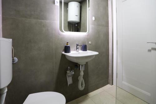 a bathroom with a sink and a toilet and a mirror at Airport Stay Apartments in Surčin
