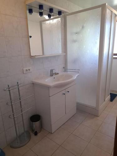 une salle de bain blanche avec un lavabo et un miroir dans l'établissement Pélégrine, à Gabriac