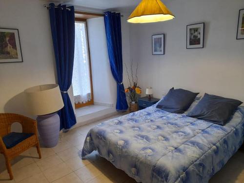 une chambre avec un lit avec des draps bleus et une fenêtre dans l'établissement Pélégrine, à Gabriac