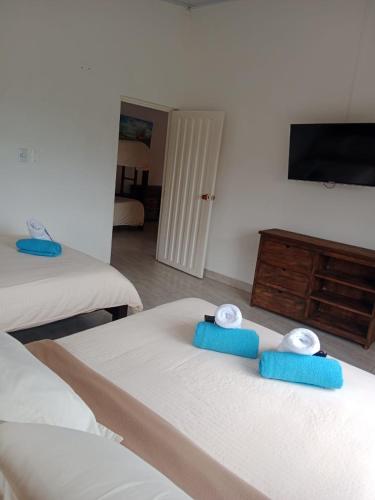 a bedroom with two beds with blue towels on them at Hotel Cafetero Valparaíso in La Vega
