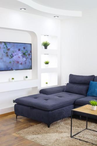 a living room with a blue couch and a tv at Airport Stay Apartments in Surčin