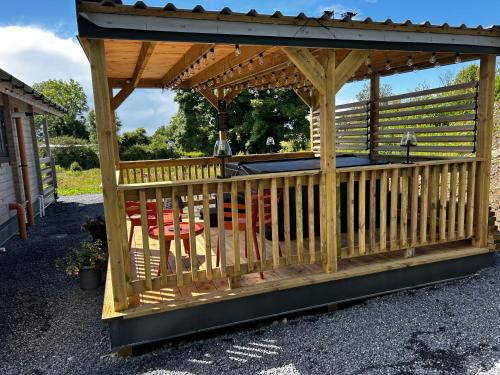 a wooden gazebo with a table and chairs at LITTLE ROCK RETREAT Log Cabin with Hot Tub in Westmeath