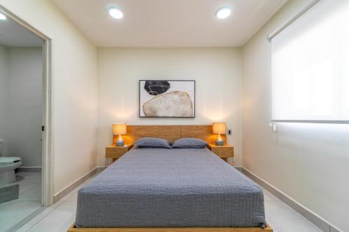 普拉亚卡门Penthouse with Jungle View Terrace Gym Pool HotTub的一间卧室，有一张床，两盏灯和一扇窗户