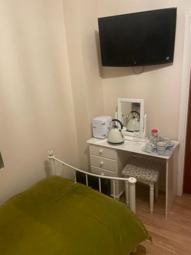 a bedroom with a desk with a tv on the wall at Dolphin Inn in Llanymynech