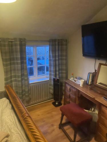 a bedroom with a bed and a desk and a television at Dolphin Inn in Llanymynech