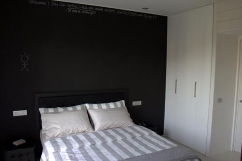 a bedroom with a black wall and a bed with white pillows at Home BB Milano in Milan