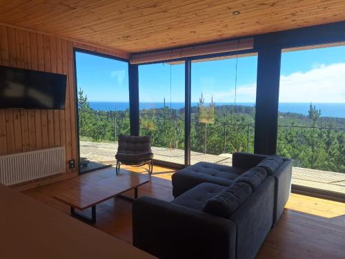 a living room with a couch and a large window at Casa Bosquemar Boyeruca in Vichuquén