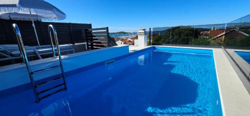 una piscina blu con scala e ombrellone di Vila Biser Vodice a Vodice