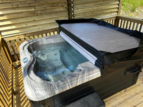a jacuzzi tub with a lid on top at LITTLE ROCK RETREAT Log Cabin with Hot Tub in Westmeath