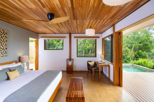 a bedroom with a bed and a swimming pool at El Remanso Rainforest Lodge in Puerto Jiménez
