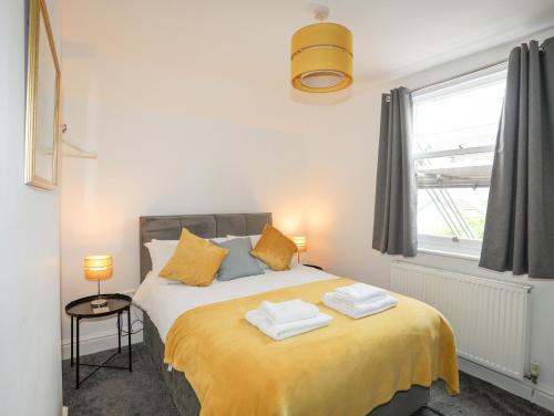 a bedroom with a bed with yellow sheets and a window at Bodafon View in Llandudno
