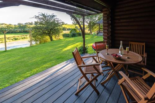 eine Holzterrasse mit einem Tisch und Stühlen darauf in der Unterkunft Ta Mill Cottages & Lodges - Brookview Lodge 2 in Launceston