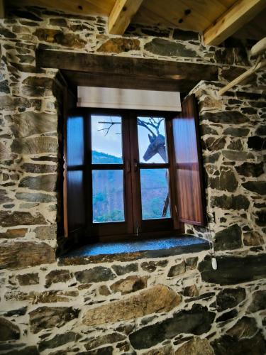 a window in a stone building with a view at Cantinho do Talasnal in Talasnal