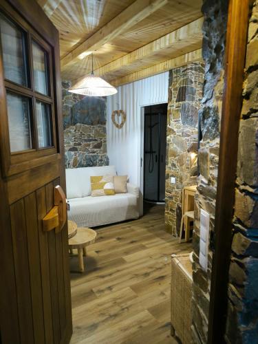a living room with a couch and a stone wall at Cantinho do Talasnal in Talasnal