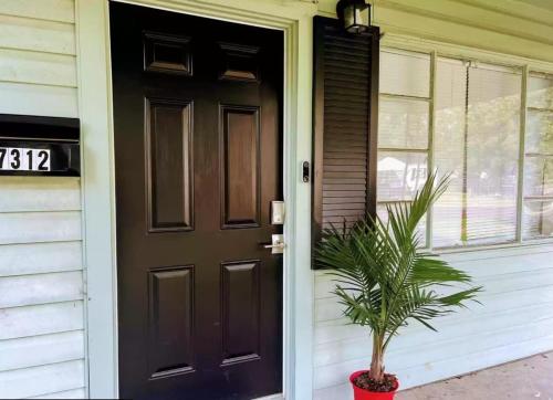 a black door on a house with a potted plant at Spacious 4BR Home with 2 Baths & Fun Game Room in Birmingham