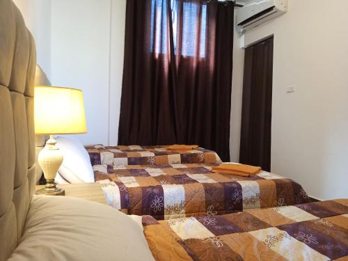 two beds in a bedroom with a lamp and a window at Petra Planet in Wadi Musa