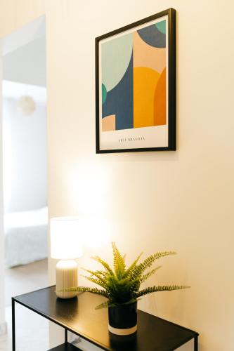 une table avec une plante sur un mur avec une image dans l'établissement HELIANTHE - Cosy et spacieux refait à neuf tout confort, à Saint-Étienne