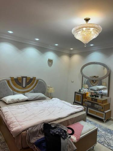 a bedroom with a large bed and a chandelier at الخمايل الشيخ زايد in Kafr Abū ʼumaydah