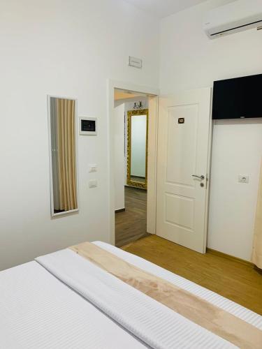 a white bedroom with a bed and a hallway at Vila Franko in Berat