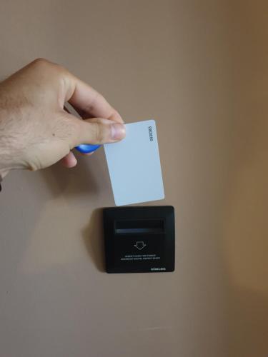 a hand holding a credit card next to a black box at LA Comfy AP in Sarandë
