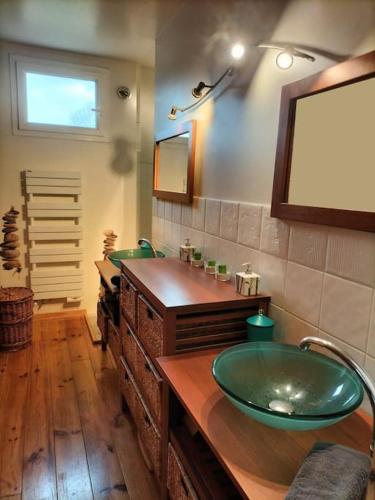 La salle de bains est pourvue de 2 lavabos verts et d'un miroir. dans l'établissement Le Chalet de l'Odet, à Quimper