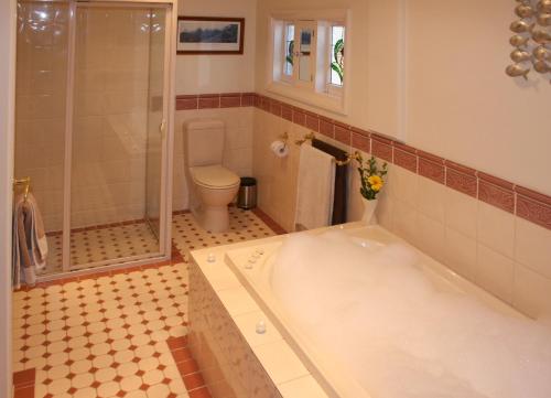 a bathroom with a bath tub and a toilet at Oats Cottage in Hahndorf