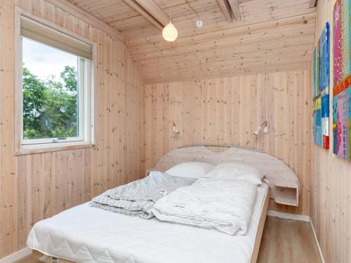 a bed in a wooden room with a window at 5 star holiday home in Hadsund-By Traum in Hadsund