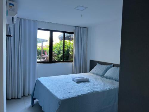 a bedroom with a white bed with a window at Apartamento, Paraíso das Águas, Guarajuba, Bahia in Camacari