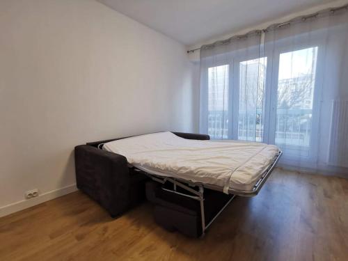 un lit dans une chambre avec une grande fenêtre dans l'établissement Superbe studio at 20 mins from Champs Elysées av, à Asnières-sur-Seine