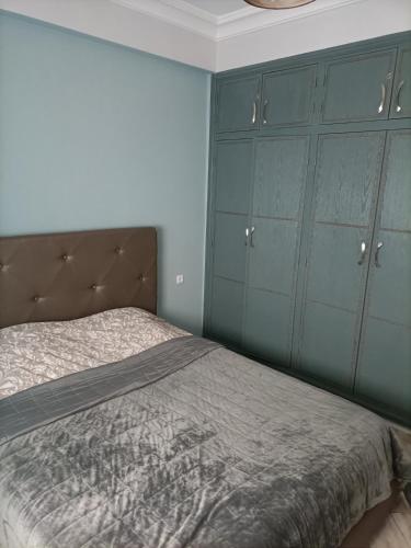 a bedroom with a bed with blue cabinets at Jolie appartement in Kenitra