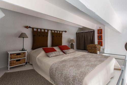 Un dormitorio con una gran cama blanca con almohadas rojas. en L'Intimate Sahara - Piscine - Tennis - Clim, en Cap d'Agde
