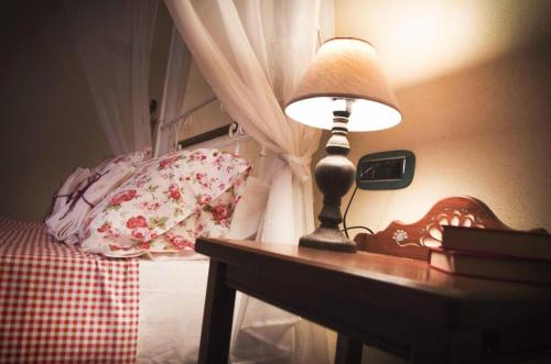 a lamp sitting on a table next to a bed at BnB Inn - Cyclists & Bikers - CAMERE CON BAGNO PRIVATO-PARCHEGGIO INTERNO PER MOTO e BICI -ENERGETIC BREAKFAST extra in Làconi