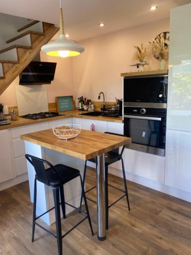 une cuisine avec une table en bois et des appareils noirs dans l'établissement Maison de village entre lac et montagne, à La Motte-Servolex