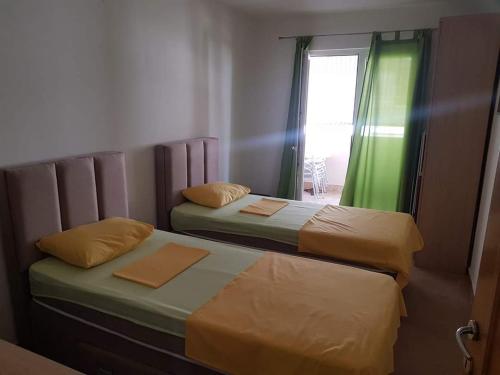 two twin beds in a room with a window at Apartman Cristo Becici in Rafailovici