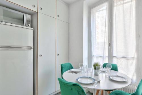 une salle à manger blanche avec une table blanche et des chaises vertes dans l'établissement Appartement QUARTIER EMILY IN PARIS NOTRE DAME, à Paris