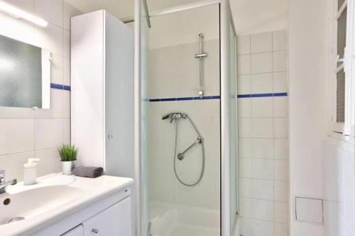 une salle de bain blanche avec une douche et un lavabo dans l'établissement Appartement QUARTIER EMILY IN PARIS NOTRE DAME, à Paris