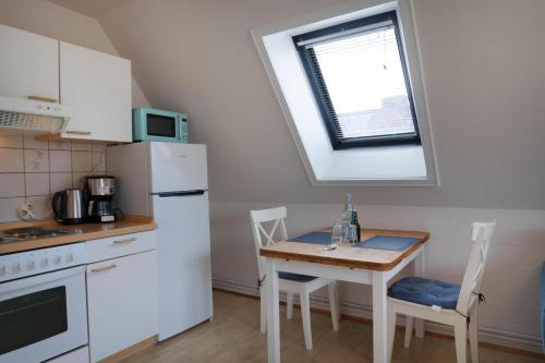 a kitchen with a table and a white refrigerator at Ferienwohnung Kleine Auszeit Nr 4 in Maasholm