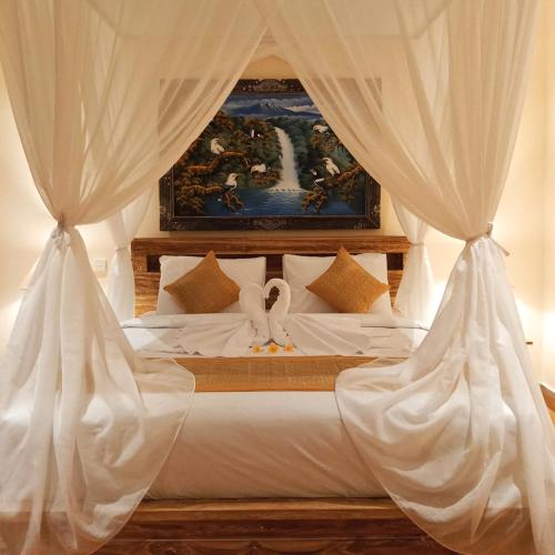 a bedroom with a bed with white drapes at Royal Amertha Ubud Jungle View in Gianyar