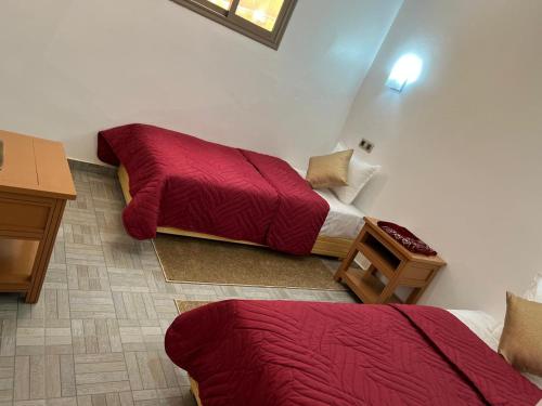 a room with two beds and a table and a desk at Maison de KAOUKI in Essaouira