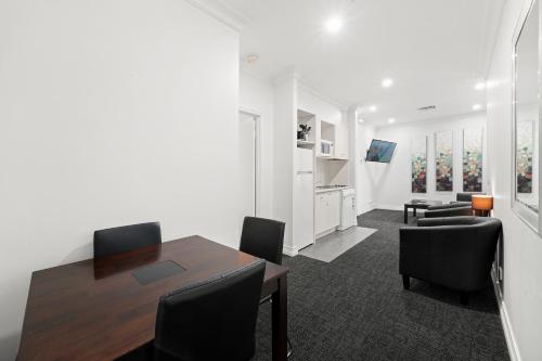 a living room with a dining room table and chairs at Comfort Apartments Melbourne Central in Melbourne