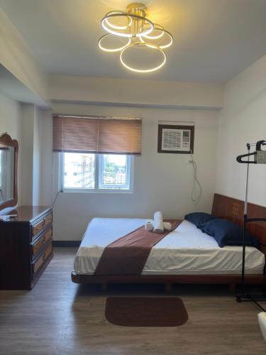 a bedroom with a bed and a television and a chandelier at Jojies Crib Symfoni Tower 2 Bossa Guadalupe in Cebu City