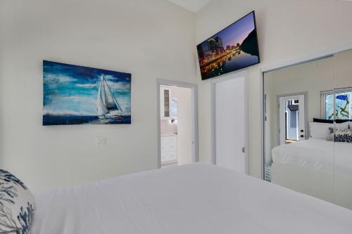 a white bedroom with a bed and a tv on the wall at The Shining Sea A in Oceanside
