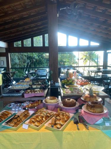 a table filled with lots of different types of pastries at Pousada Sol e Cia Tur in Caraguatatuba