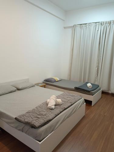 two twin beds in a room with a window at Sri Indah Pool Condostay in Sandakan