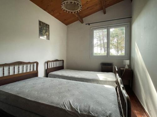 une chambre avec deux lits et une fenêtre dans l'établissement Villa 4 pièces à La Palmyre, proche mer et commerces, patio, barbecue, animaux admis, parking inclus - FR-1-705-40, aux Mathes
