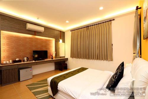 a hotel room with a bed and a television at Ai Wan Jia B&B in Luodong