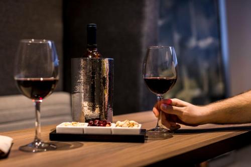 a person holding two glasses of wine and a plate of food at Kharma Suites in Puebla