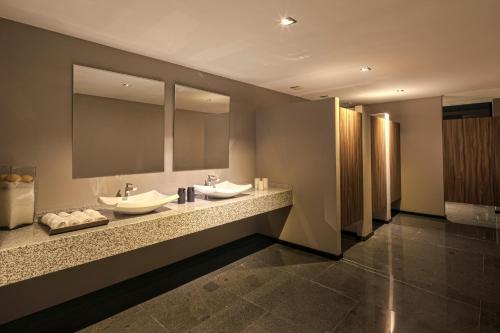 a bathroom with two sinks and two mirrors at Kharma Suites in Puebla