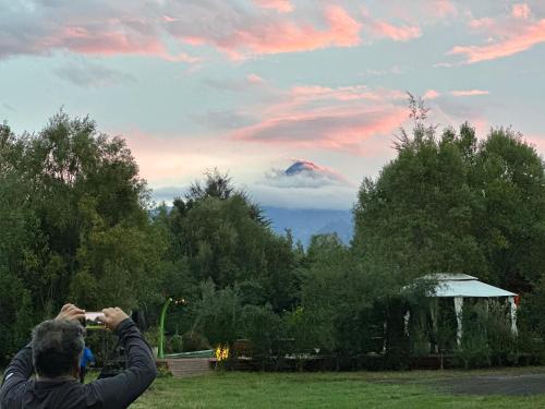 a man taking a picture of a kite in the sky at Cabañas Natural Park Lodge Pucón in Pucón