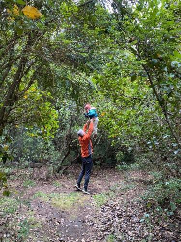 a man carrying a child on his shoulders in the woods at Cabañas Natural Park Lodge Pucón in Pucón